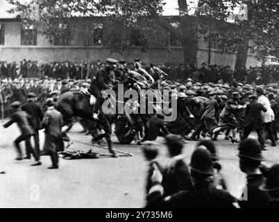 Émeutes du chômage à Londres . La police montée en charge à Whitehall : Une photographie pleine de mouvement - hommes tombant et femmes spectatrices courant - sur le sol, une des banderoles des manifestants. Au cours des émeutes, une quarantaine de personnes dans la foule ont été blessées, dont vingt ont été transportées à l'hôpital, et dix des policiers. À cinq heures, les émeutiers s'étaient dispersés, et la procession s'éloigna. Dès le début de la grève du charbon , le chômage a augmenté dans divers districts. 18 octobre 1920 Banque D'Images