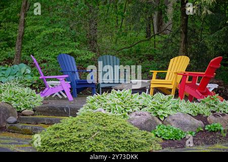 Groupe de chaises colorées dans un jardin fleuri Banque D'Images