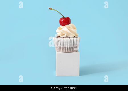 Support décoratif avec délicieux cupcake à la cerise sur fond bleu Banque D'Images