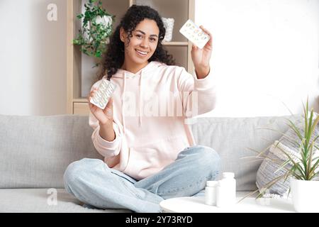 Jeune femme afro-américaine avec de l'huile de poisson à la maison Banque D'Images