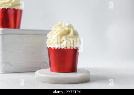 cupcakes rouges avec un grand tourbillon de crème au beurre, cupcakes dans des doublures de feuille rouge avec crème au beurre à la vanille, cupcakes givrés sur un fond blanc Banque D'Images