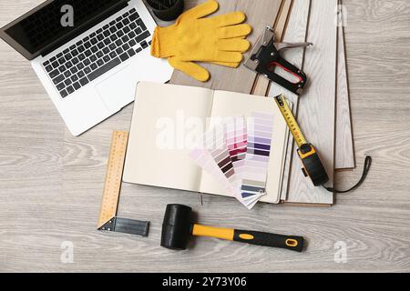 Outils, ordinateur portable, palettes de couleurs et planches stratifiées sur le sol Banque D'Images