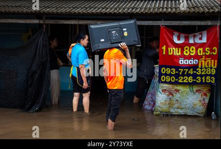 Chiang mai, Thaïlande. 27 septembre 2024. Un résident se tient dans les eaux de crue, portant une télévision, après que des crues éclair ont inondé la zone à la suite de pluies continues. Les inondations à Chiang mai ont été causées par des précipitations continues, magasin d'électronique, ce qui a entraîné le ruissellement de Doi Suthep se jetant dans les zones de basse altitude. Les fortes pluies ont également provoqué le débordement de la rivière Ping à plusieurs endroits de la ville, endommageant des maisons et provoquant des embouteillages sur de nombreuses routes. (Photo de Pongmanat Tasiri/SOPA images/Sipa USA) crédit : Sipa USA/Alamy Live News Banque D'Images