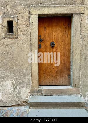 La photographie capture une vue détaillée d'une ancienne porte médiévale en bois et en métal, située dans les rues d'une ville européenne historique. Banque D'Images
