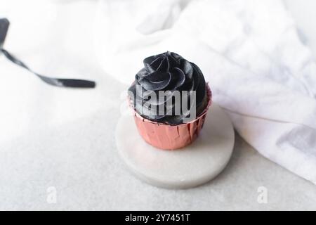 Glaçage noir sur cupcakes roses avec un fond blanc, cupcakes en feuilles roses avec crème au beurre noire Banque D'Images