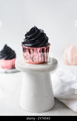 Glaçage noir sur cupcakes roses avec un fond blanc, cupcakes en feuilles roses avec crème au beurre noire Banque D'Images