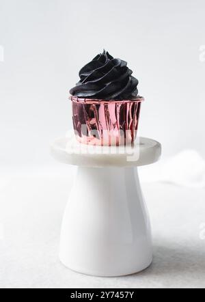 Glaçage noir sur cupcakes roses avec un fond blanc, cupcakes en feuilles roses avec crème au beurre noire Banque D'Images