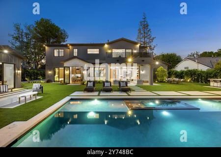 Luxueuse maison moderne avec piscine et pelouse bien entretenue, capturée au crépuscule. Banque D'Images