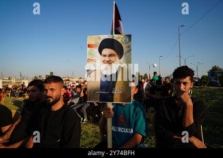 Mossoul, Irak. 27 septembre 2024. Partisan de la faction armée Kataeb Sayyid al-Shuhada (membre des forces hachées al-Shaabi/de mobilisation populaire ou PMF) tient un portrait du chef du Hezbollah Hassan Nasrallah lors d'une manifestation de solidarité contre l'agression israélienne contre le Liban et la Palestine près de la Grande Mosquée (non visible) de Mossoul dans la ville de Mossoul. Crédit : SOPA images Limited/Alamy Live News Banque D'Images