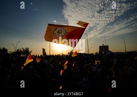 Mossoul, Irak. 27 septembre 2024. Un partisan silhouette de la faction armée Kataeb Sayyid al-Shuhada (membre des forces hachées al-Shaabi/de mobilisation populaire ou PMF) tient un drapeau lors d'une tribune de solidarité contre l'agression israélienne contre le Liban et la Palestine près de la Grande Mosquée (non en veiw) de Mossoul dans la ville de Mossoul, en Irak. Crédit : SOPA images Limited/Alamy Live News Banque D'Images