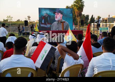 Mossoul, Irak. 27 septembre 2024. Les partisans de la faction armée Kataeb Sayyid al-Shuhada (membre des forces hachées al-Shaabi/de mobilisation populaire ou PMF) regardent un discours vidéo d'Abu Ala al-Walai, chef de Kataeb Sayyid al-Shuhada lors d'une manifestation de solidarité contre l'agression israélienne contre le Liban et la Palestine près de la Grande Mosquée (non visible) de Mossoul, dans la ville de Mossoul, en Irak. Crédit : SOPA images Limited/Alamy Live News Banque D'Images