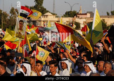 Mossoul, Irak. 27 septembre 2024. Les partisans de la faction armée Kataeb Sayyid al-Shuhada (membre des forces hachées al-Shaabi/de mobilisation populaire ou PMF) tiennent un drapeau lors d'une manifestation de solidarité contre l'agression israélienne contre le Liban et la Palestine près de la Grande Mosquée (non visible) de Mossoul dans la ville de Mossoul, en Irak. (Photo de Ismael Adnan/SOPA images/SIPA USA) crédit : SIPA USA/Alamy Live News Banque D'Images