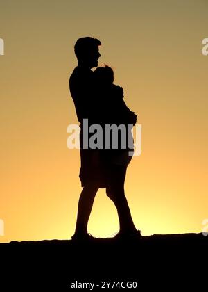 Une série de silhouettes captivantes représentant un couple partageant de tendres moments au coucher du soleil, créant une atmosphère sereine et romantique. Banque D'Images