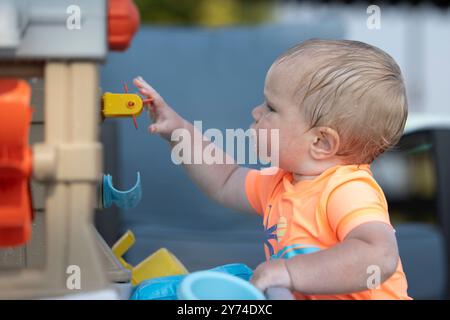 Enfant de dix mois cherchant un jouet. Banque D'Images