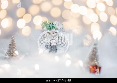 Concept de déoration de Noël en vacances avec un ange en porcelaine, fausse neige blanche pour un décembre festif. En arrière-plan sont des boules de bokeh faites de ligh Banque D'Images