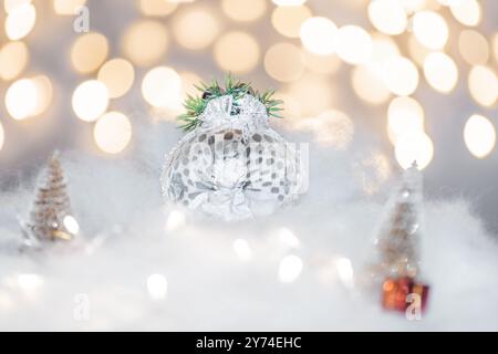 Concept de déoration de Noël en vacances avec un ange en porcelaine, fausse neige blanche pour un décembre festif. En arrière-plan sont des boules de bokeh faites de ligh Banque D'Images