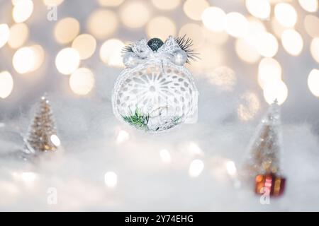 Concept de déoration de Noël en vacances avec un ange en porcelaine, fausse neige blanche pour un décembre festif. En arrière-plan sont des boules de bokeh faites de ligh Banque D'Images