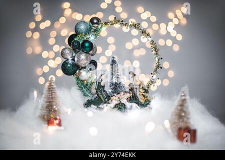 Concept de déoration de Noël en vacances avec un bébé Jésus et les parents, fausse neige blanche pour un décembre festif. En arrière-plan sont des boules de bokeh M. Banque D'Images