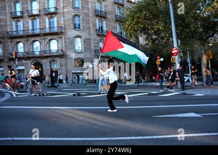 Barcelone, Espagne. 27 septembre 2024. Une jeune fille court avec un drapeau palestinien à la main le long de la rue Diagonal de Barcelone dans le cadre de la manifestation de masse en faveur de la Palestine et du Liban. Près de 20 000 personnes ont défilé lors de la manifestation de masse à Barcelone en soutien aux peuples palestinien et libanais. Crédit : SOPA images Limited/Alamy Live News Banque D'Images