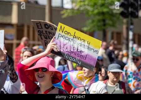 Non-binary people deserve to be recognised legally. Woman in summer hat holding a handmade sign at Helsinki Pride 2024 Parade in Helsinki, Finland. Stock Photo