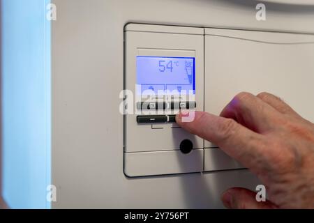 Une personne qui règle les différentes fonctions de commande d'une chaudière de chauffage domestique en préparation de l'hiver. Un concept d'utilisation de la technologie. Banque D'Images