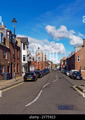 L'extrémité inférieure de Arbroath High Street regardant vers le nord, avec un mélange de logements et de propriétés commerciales le long de la route avec des voitures garées. Banque D'Images