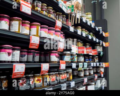 Cremona, Italie 26 septembre 2024 des pots de diverses confitures et de miel sont soigneusement disposés sur les étagères, remplissant une allée de supermarché avec une couleur vibrante Banque D'Images