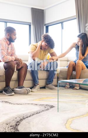 Divers amis se réconfortant, assis sur le canapé dans le salon, montrant le soutien, à la maison Banque D'Images