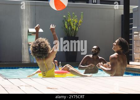 Jouer avec le ballon de plage, divers amis profitant de la fête de la piscine le jour ensoleillé, à la maison Banque D'Images