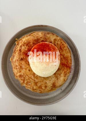 Frittata espagnole, plat commun en Espagne à base d'œufs et de pommes de terre. Garniture de mayonnaise et paprika. Servi sur une assiette, puis sur fond blanc. Banque D'Images