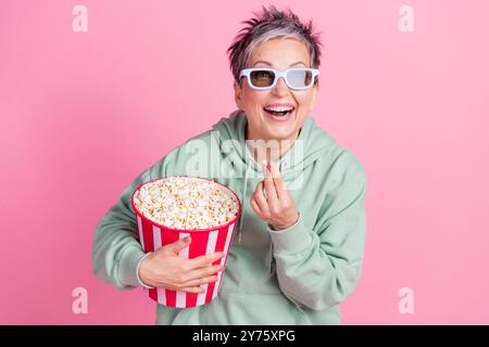 Photo de drôle de bonne humeur Lady Wear kaki Hoodie Watch film manger pop corn isolé fond de couleur rose Banque D'Images