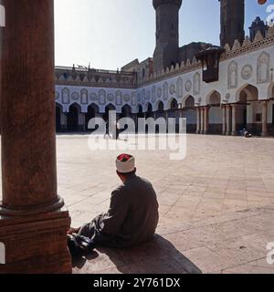 Ein Mann sitzt in der sonne in den Colonnaden vom Innenhof der al Azhar Moschee in Kairo, Ägypten um 1987. Banque D'Images