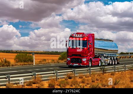 Camion-citerne pour liquides alimentaires circulant sur une autoroute au milieu de champs de culture. Banque D'Images