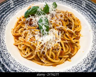 Une assiette de spaghetti bolognaise avec du parmesan râpé sur le dessus dans un restaurant italien Banque D'Images