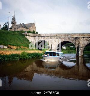 Kleine gotische Kirche an einer Steinbogenbrücke über den Fluss Oust in der Gemeinde Val d'Oust in der Bretagne, Frankreich um 1984. Banque D'Images