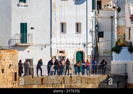 Un groupe de personnes profitant de la vue depuis une terrasse dans la via Porto, la vieille ville de Polignano a Mare, en Italie. Banque D'Images