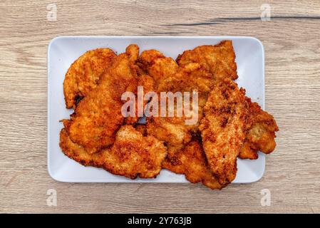 Côtelettes de filet de poulet enrobées de chapelure et frites dans une casserole couchée sur une assiette. Banque D'Images