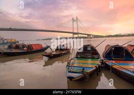 Des bateaux sur la rivière Ganes avec vue sur le câble sont restés au pont Vidyasagar Setu au coucher du soleil à Kolkata, en Inde Banque D'Images