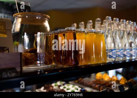 Une fenêtre de café avec des rangées soigneusement affichées de bouteilles en verre de jus et d'eau Banque D'Images