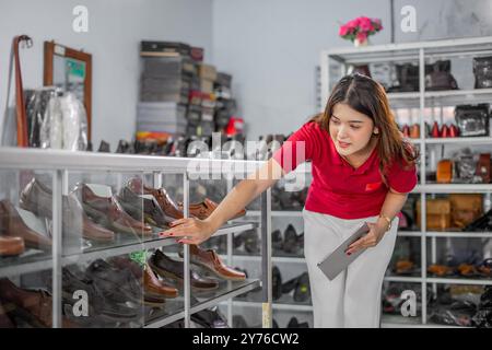 personnel féminin asiatique à la recherche de fournitures de produits dans l'étagère d'affichage Banque D'Images