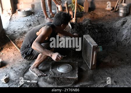 Ambatolampy, fonderie artisanale d'aluminium. Ouvrier démoulant. Hauts plateaux centraux, région de Vakinankaratra, Madagascar. Banque D'Images