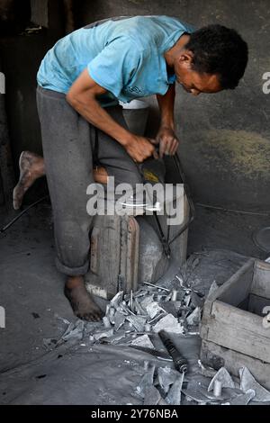 Ambatolampy, fonderie artisanale d'aluminium. Travailleur polissant le produit. Hauts plateaux centraux, région de Vakinankaratra, Madagascar. Banque D'Images