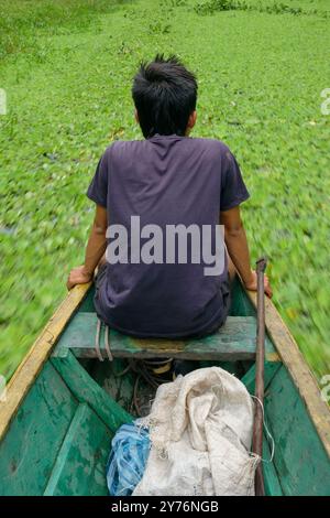 Un jeune marin navigue à travers le fleuve amazone sur un bateau traditionnel en bois Banque D'Images