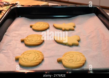 Un plateau de biscuits d'Halloween avec des formes de citrouille et de feuille. Les biscuits sont sur un papier parchemin et sont prêts à être cuits Banque D'Images