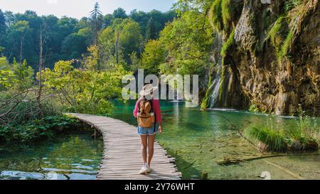 En flânant le long des sentiers en bois des lacs de Plitvice, le visiteur bénéficie d’une vue imprenable sur les eaux turquoises et la verdure luxuriante sous un ciel clair. La sérénité de la nature invite à l'exploration. Banque D'Images