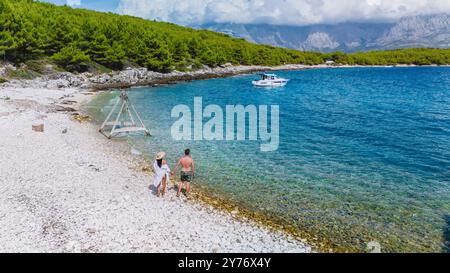 Quelques promenades le long de la plage de galets de Brac Island, entourée de verdure luxuriante et d'eaux cristallines Banque D'Images