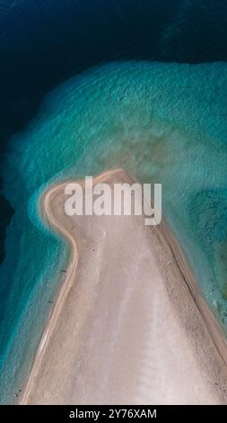 Les croates de Zlatni Rat Beach s'étendent dans les eaux turquoises, soulignant la beauté naturelle de l'île de Brac. Les visiteurs apprécient l'atmosphère tranquille, avec des bains de soleil et des nageurs Banque D'Images