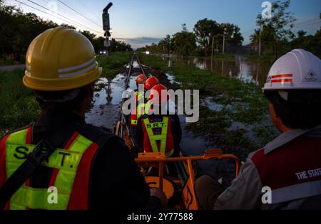 Chiang mai, Thaïlande. 27 septembre 2024. Des fonctionnaires et des travailleurs de la Compagnie des chemins de fer d'État de Thaïlande sont assis sur un véhicule d'entretien sur les voies inondées tout en inspectant la ligne pour assurer la sécurité et la préparation des rails et des traverses après l'inondation dans la zone ferroviaire de Chiang mai. Avant la réouverture de la voie ferrée après une inondation, des inspections sont effectuées pour assurer la sécurité des passagers. L'état des voies est évalué pour s'assurer que les niveaux d'eau ne dépassent pas les normes établies et que les voies ne doivent pas être endommagées. En outre, le système de signalisation, l'équipement de commande et les limons de vitesse Banque D'Images