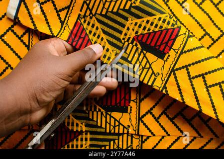 vue de dessus de couper le tissu ankara avec des ciseaux, flatlay de tissu de cire nigérian Banque D'Images