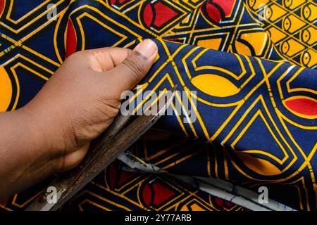 vue de dessus de couper le tissu ankara avec des ciseaux, flatlay de tissu de cire nigérian Banque D'Images